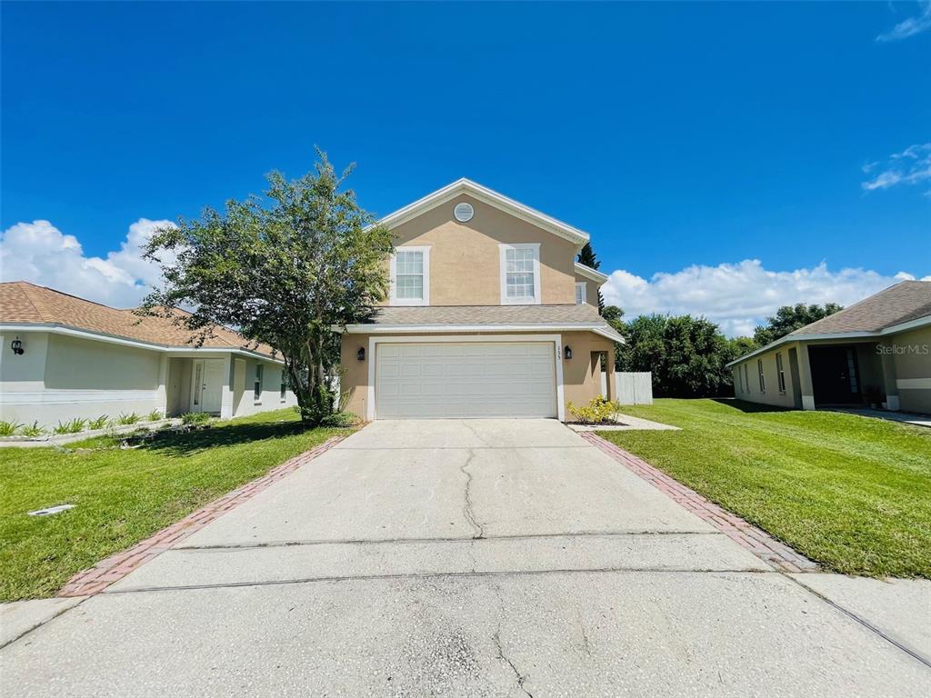 A two-story house with a beige stucco exterior, a two-car garage, and a concrete driveway — 155 OWENSHIRE CIRCLE, KISSIMMEE, FL