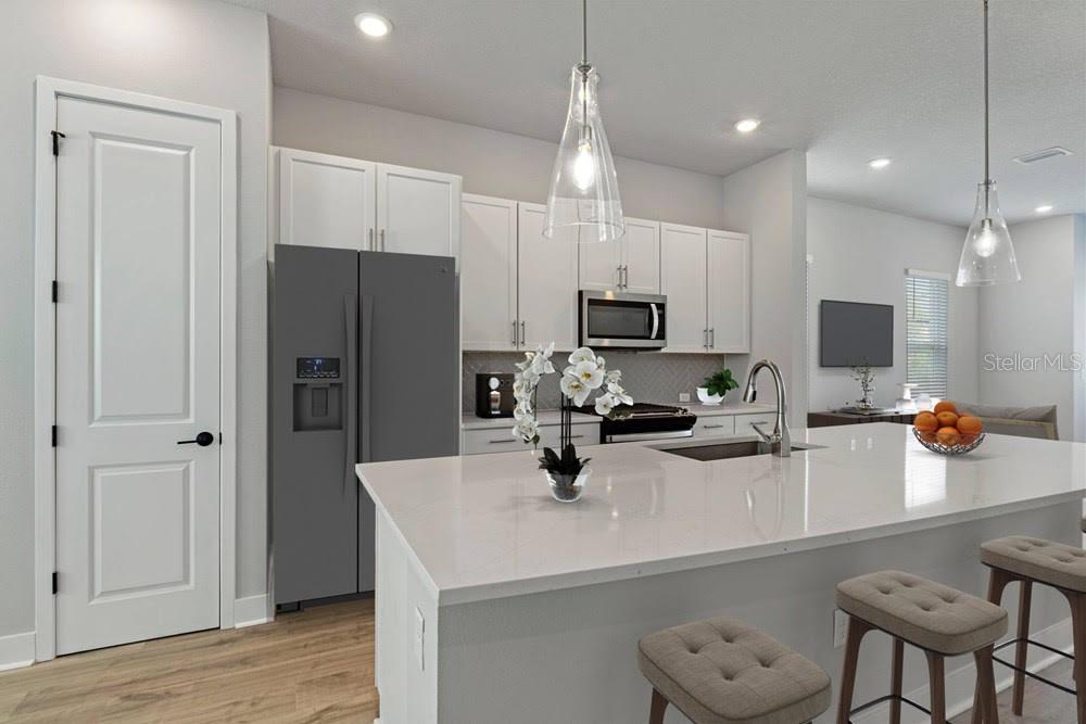 A modern kitchen features white cabinets, a large quartz island, and stainless steel appliances — 89 28TH STREET S, ST PETERSBURG, FL