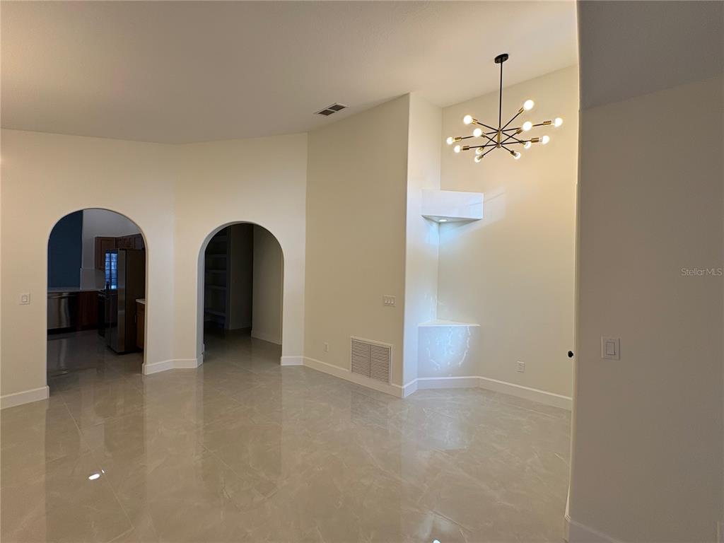 An open room features arched doorways, a modern chandelier, and light-colored tile flooring — 11215 CRYSTAL GLEN BOULEVARD, ORLANDO, FL