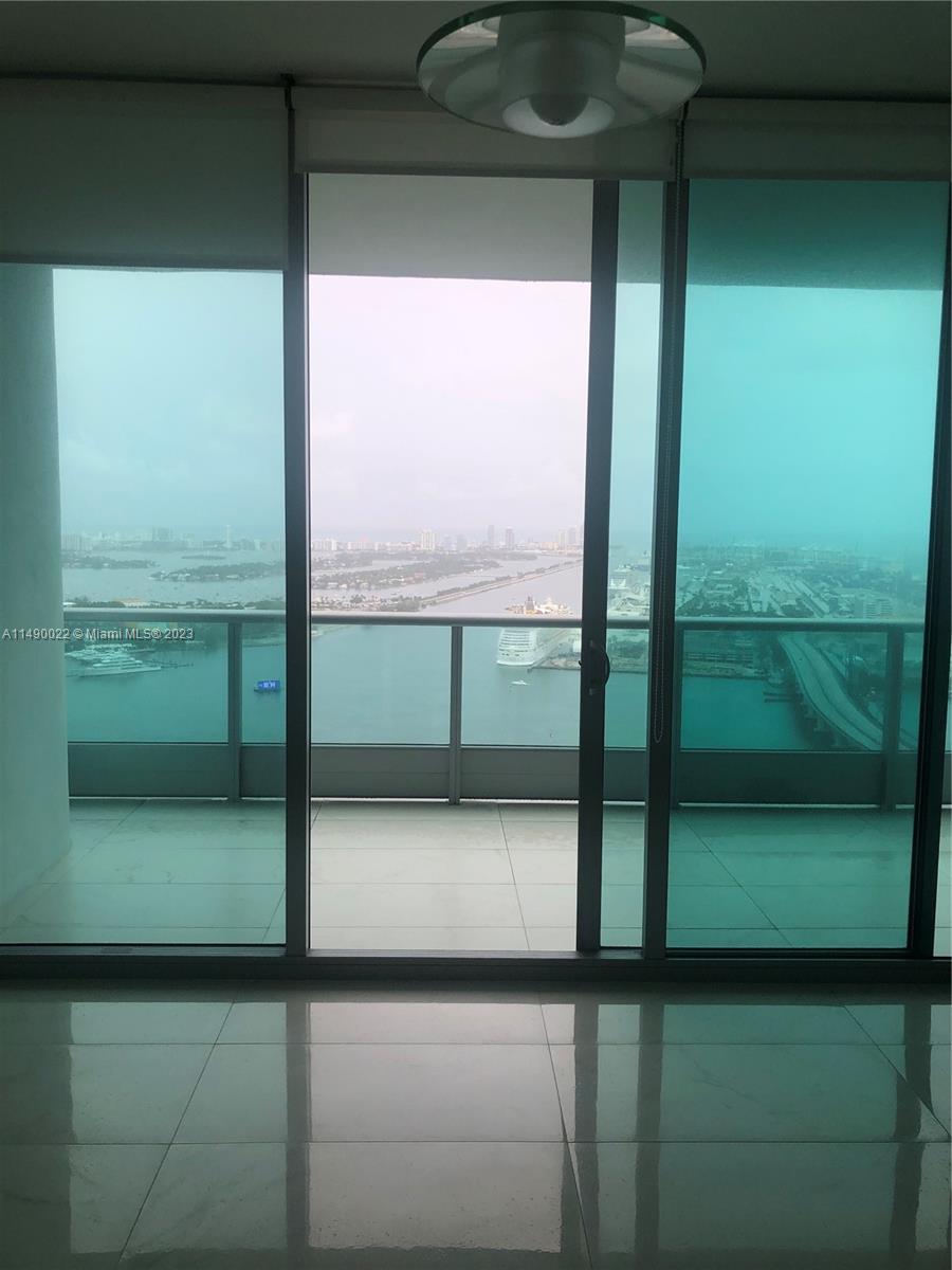 A room with floor-to-ceiling glass doors opens onto a balcony overlooking a harbor — 900 Biscayne Blvd # 4904, Miami FL 33132, MIAMI, FL