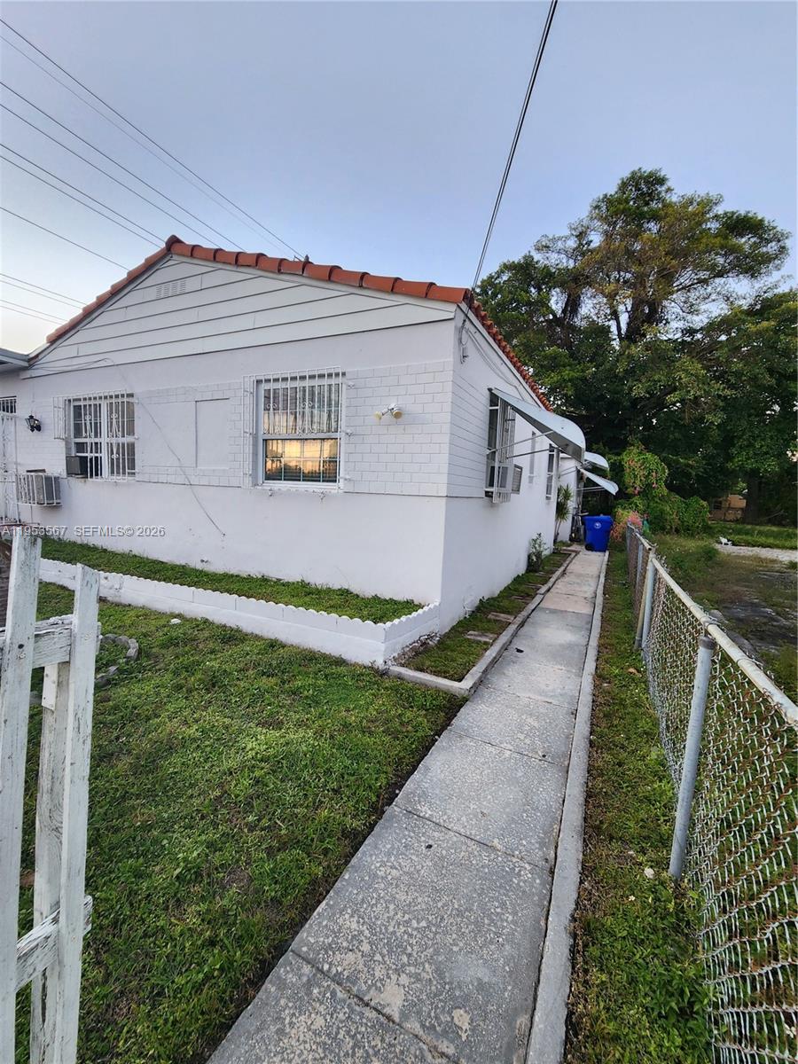 A white single-story house with a tiled roof and a white picket fence — 405 NW 64th St # 2, Miami FL 33150, MIAMI, FL