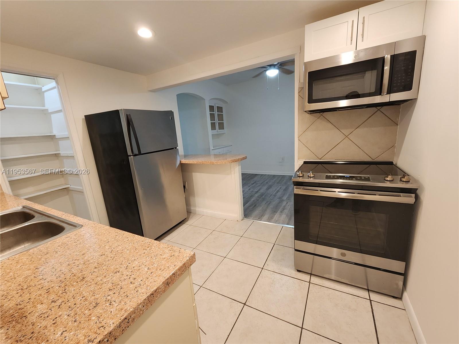A kitchen features stainless steel appliances, granite countertops, tile flooring, and an open pantry — 405 NW 64th St # 2, Miami FL 33150, MIAMI, FL
