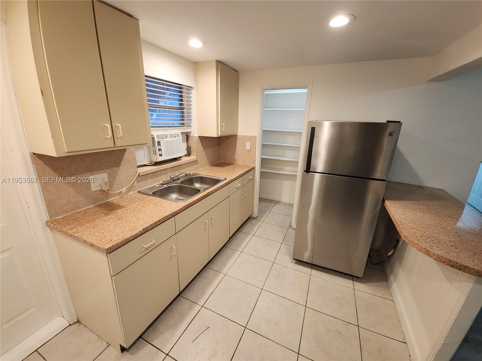 A kitchen features beige cabinets, granite countertops, a stainless steel refrigerator, and a pantry — 405 NW 64th St # 2, Miami FL 33150, MIAMI, FL