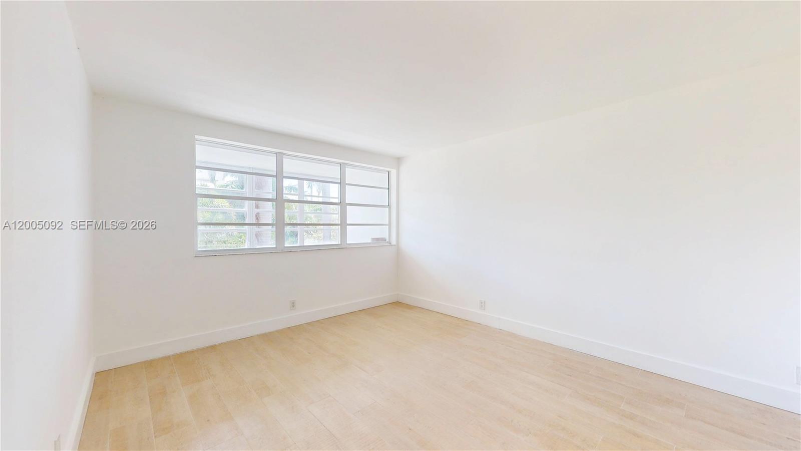 An empty room features white walls, light-colored wood-look flooring, and a large multi-pane window — 1333 E Hallandale Beach Blvd # 326, Hallandale Beach FL 33009, HALLANDALE BEACH, FL