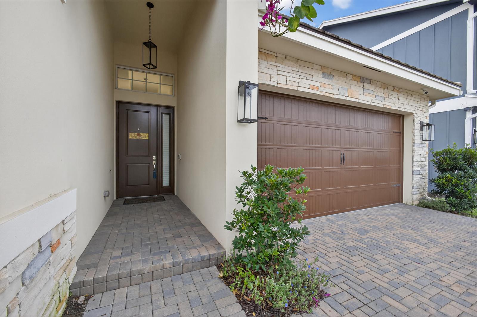 A front entryway with a brown door, stone accents, and a paved driveway — 1411 Thistle Place, Loxahatchee FL 33470, LOXAHATCHEE, FL