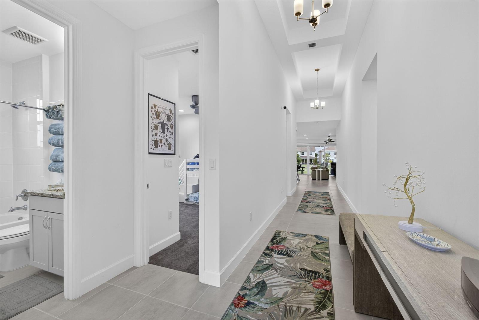 A bright hallway features tile flooring, two runner rugs, a console table, and tray ceilings — 1411 Thistle Place, Loxahatchee FL 33470, LOXAHATCHEE, FL