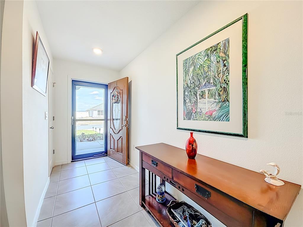 A tiled entryway features a wooden console table, a framed painting, and an open front door — 662 W FAIRWAYS VIEW DRIVE, BEVERLY HILLS, FL