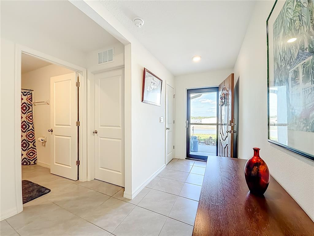 A tiled entryway features a wooden console table, a red vase, and several white doors — 662 W FAIRWAYS VIEW DRIVE, BEVERLY HILLS, FL
