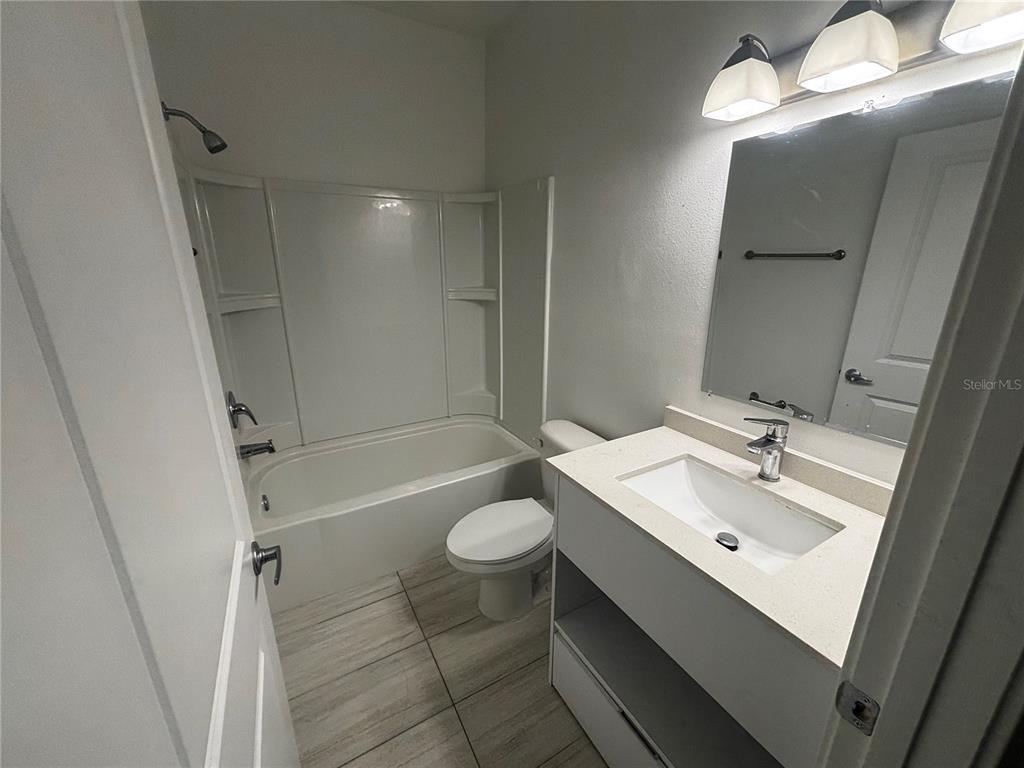A bathroom features a white vanity, a toilet, and a tub-shower combination with tiled floors — 1209 SOUTHSTATION PLACE UNIT 303, ORLANDO, FL