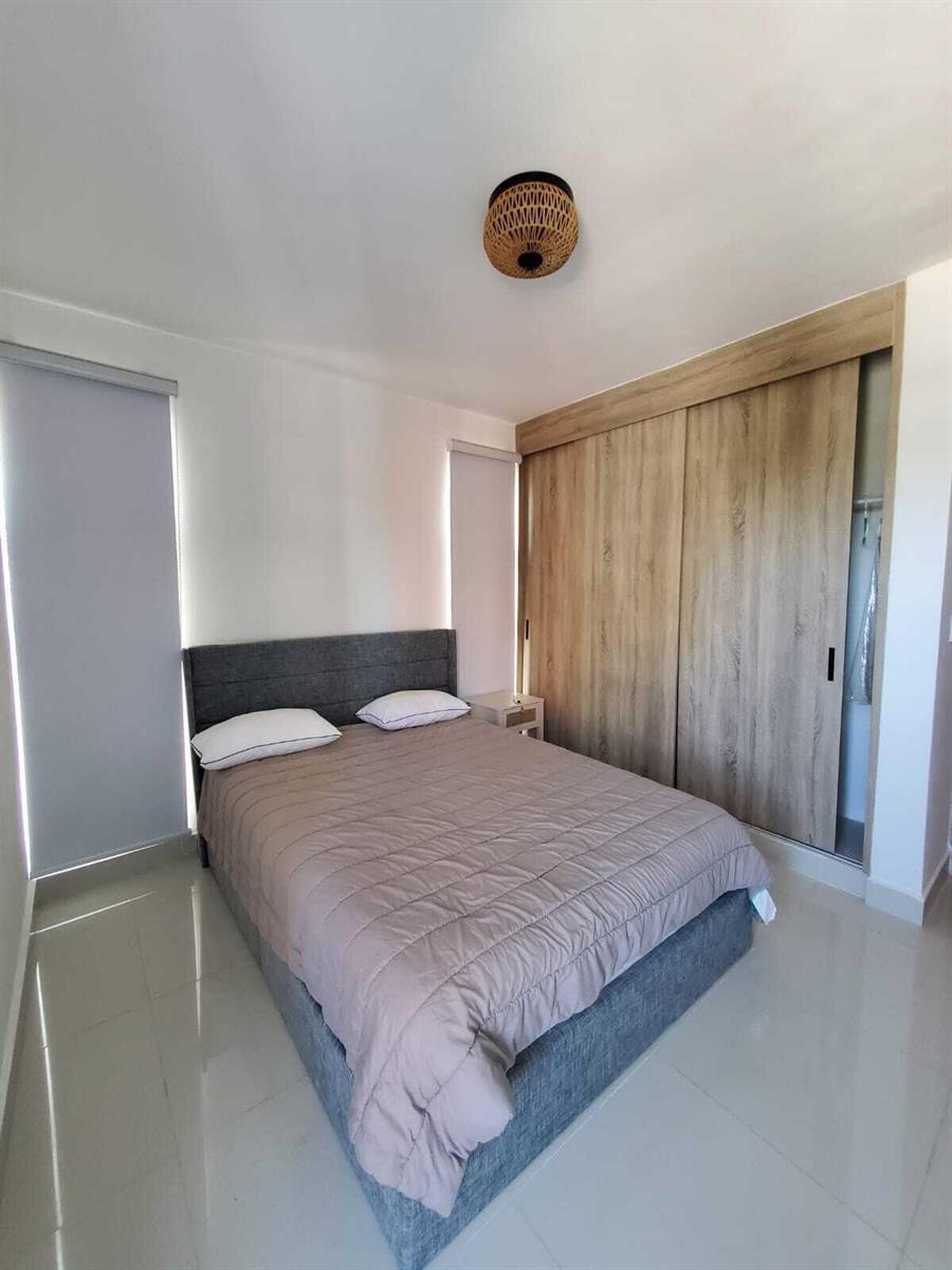 A bedroom features a gray upholstered bed, light wood sliding closet doors, and tile flooring — 50 C. Los Fereira # I8, FL