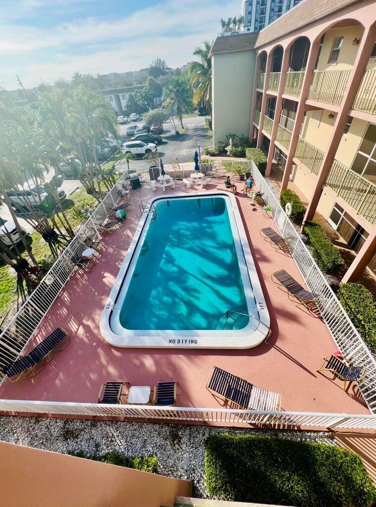 An elevated view of a rectangular swimming pool surrounded by lounge chairs and a building — 100 SE 6th Avenue # 303, Pompano Beach FL 33060, POMPANO BEACH, FL