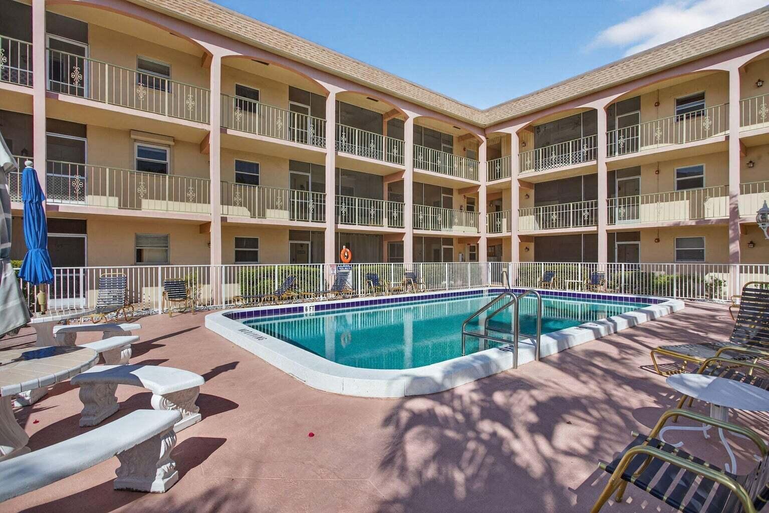 A swimming pool sits in the courtyard of a three-story apartment building with screened balconies — 100 SE 6th Avenue # 303, Pompano Beach FL 33060, POMPANO BEACH, FL