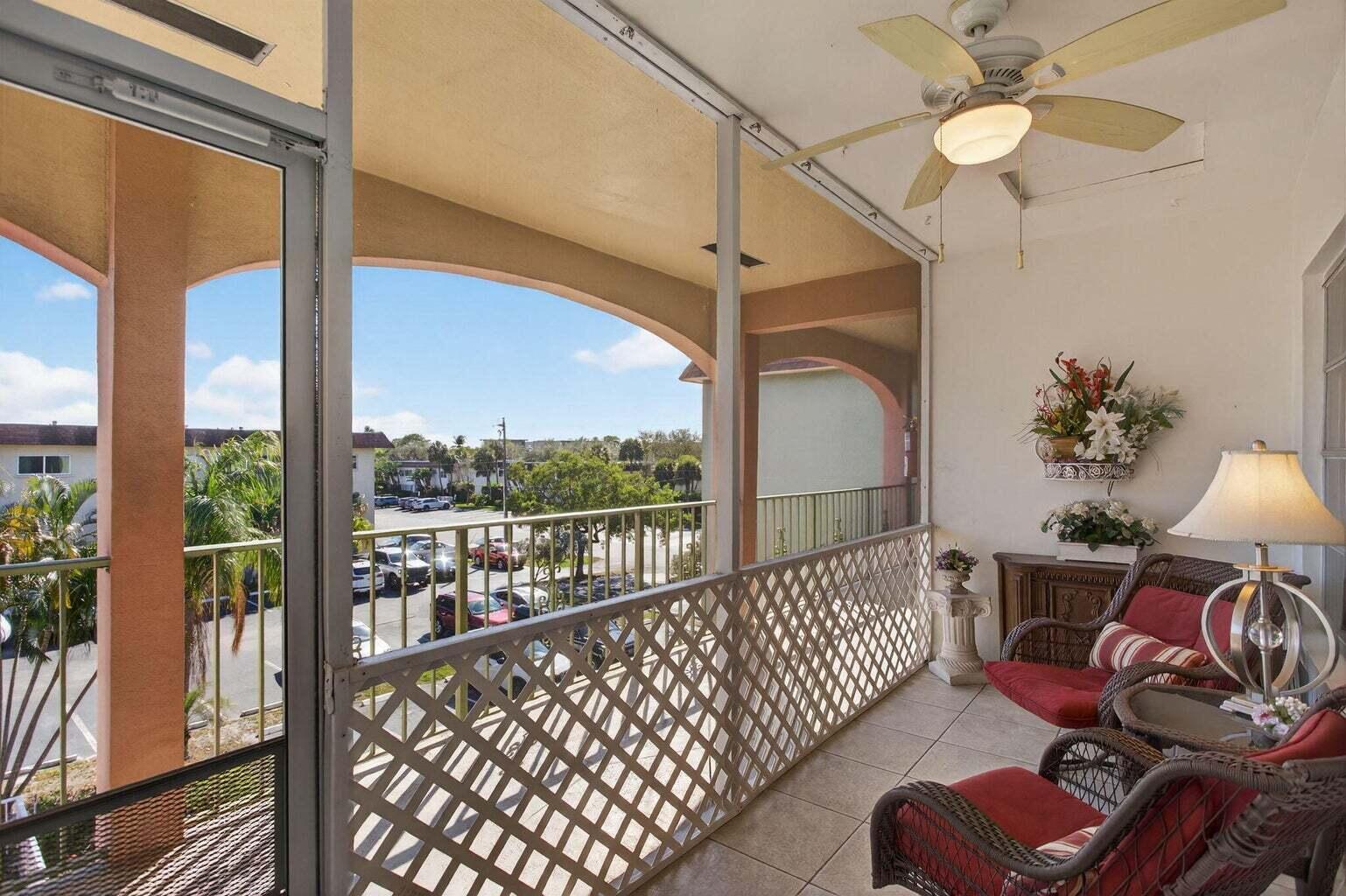 A screened-in balcony features tile flooring, wicker furniture, a ceiling fan, and a parking lot view — 100 SE 6th Avenue # 303, Pompano Beach FL 33060, POMPANO BEACH, FL