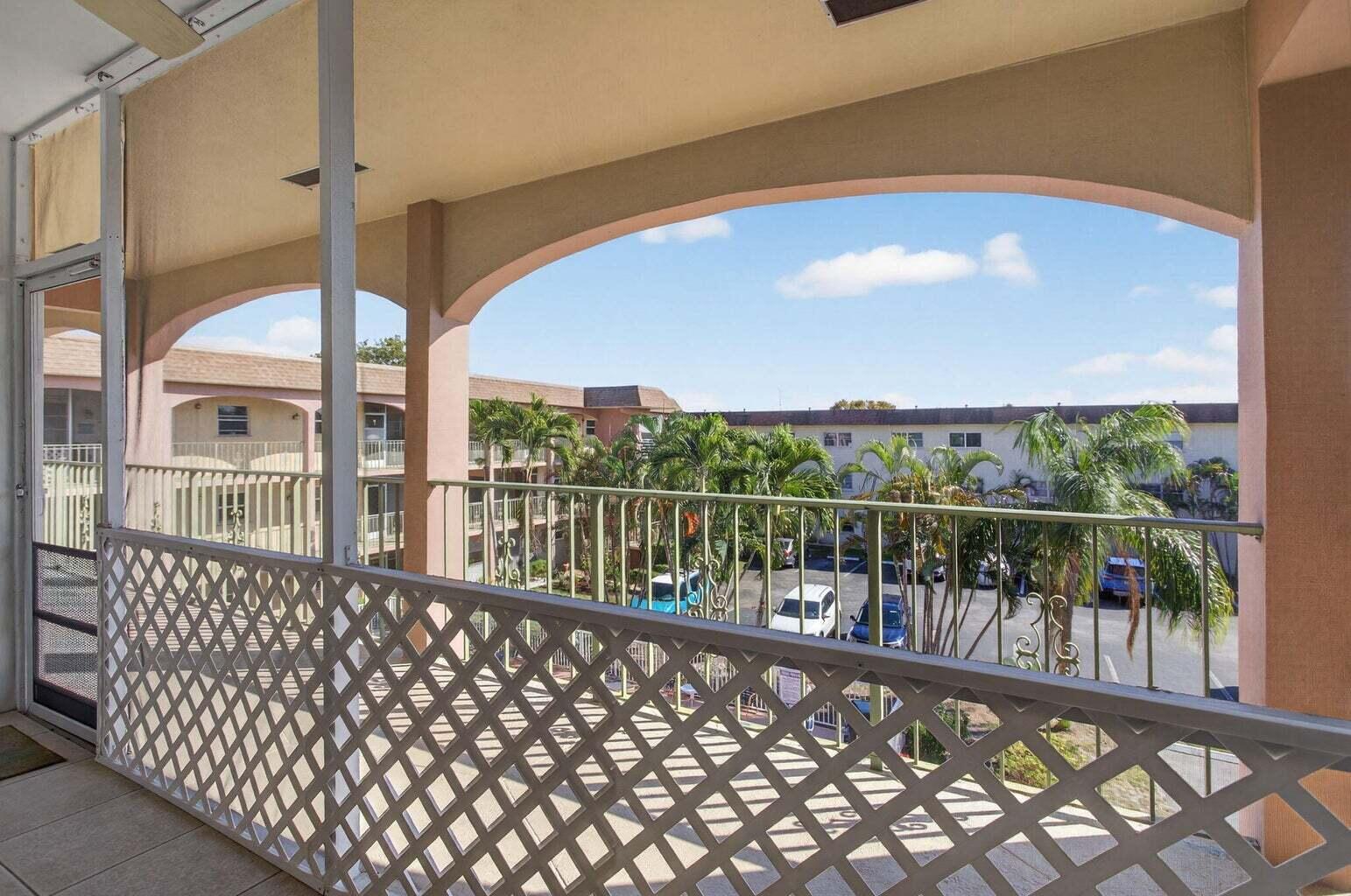 A covered balcony with a lattice railing overlooks a parking lot and palm trees — 100 SE 6th Avenue # 303, Pompano Beach FL 33060, POMPANO BEACH, FL