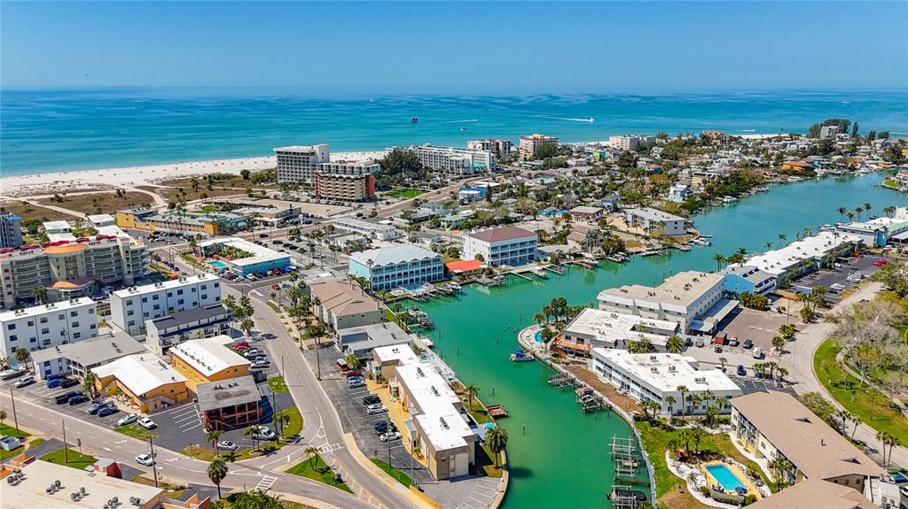 An aerial view shows a coastal town with buildings, a canal, and a sandy beach — 184 117TH AVENUE UNIT 2, TREASURE ISLAND, FL
