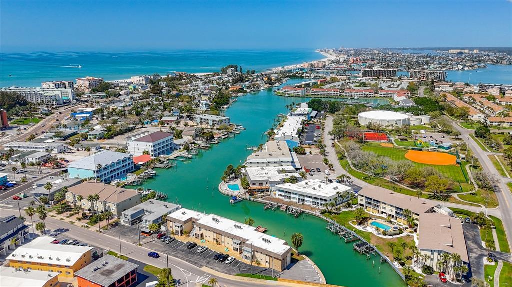 An aerial view shows a coastal waterway lined with multi-story residential buildings and parking lots — 184 117TH AVENUE UNIT 2, TREASURE ISLAND, FL