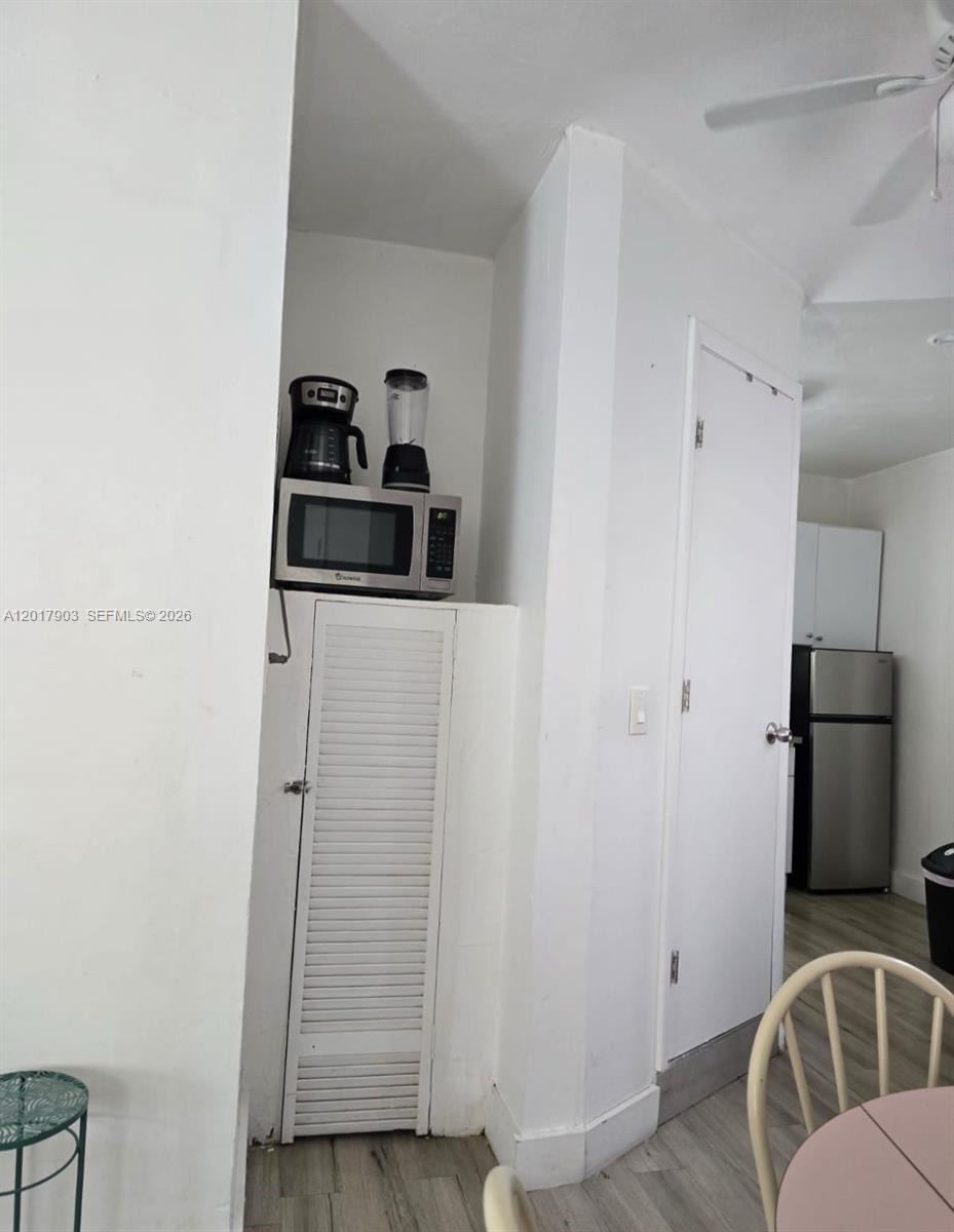 A kitchen area features a microwave on a cabinet, a refrigerator, and white walls — 109 SE 9th St # 6, Hallandale Beach FL 33009, HALLANDALE BEACH, FL