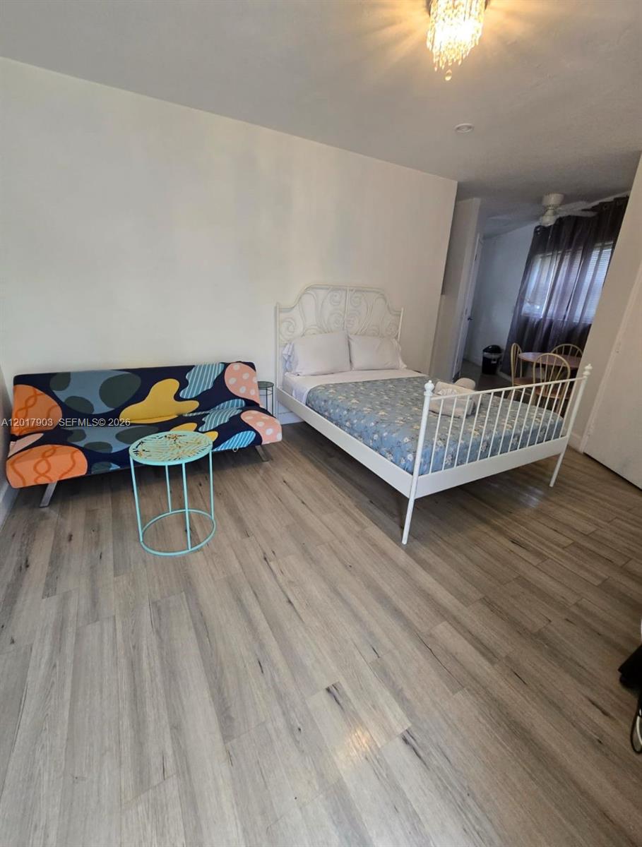 A bedroom features a white metal bed frame, a patterned futon, and wood-look flooring — 109 SE 9th St # 6, Hallandale Beach FL 33009, HALLANDALE BEACH, FL