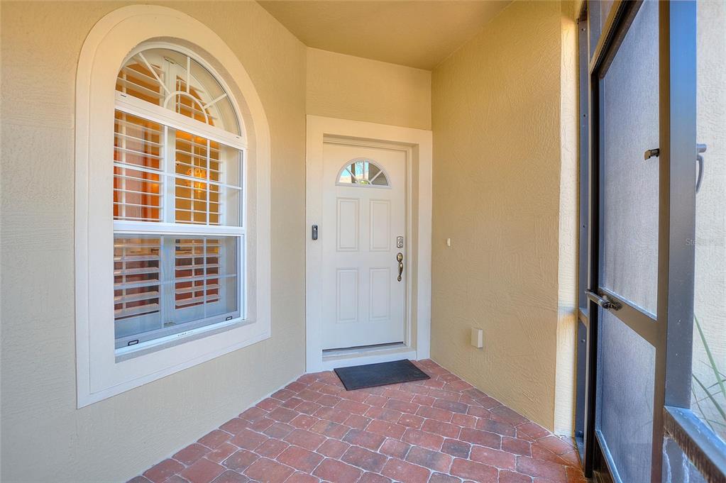 A covered entryway features a brick floor, a white front door, and an arched window — 1678 LINZ COURT, WINTER HAVEN, FL