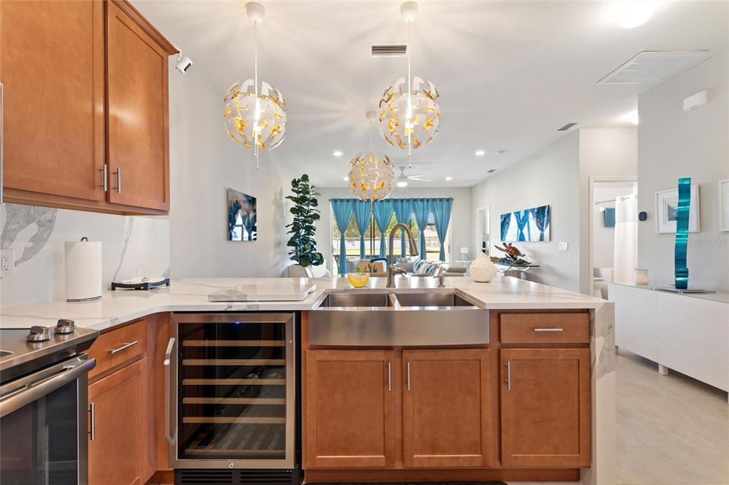 A kitchen features wood cabinets, a stainless steel farmhouse sink, and a wine refrigerator — 1678 LINZ COURT, WINTER HAVEN, FL