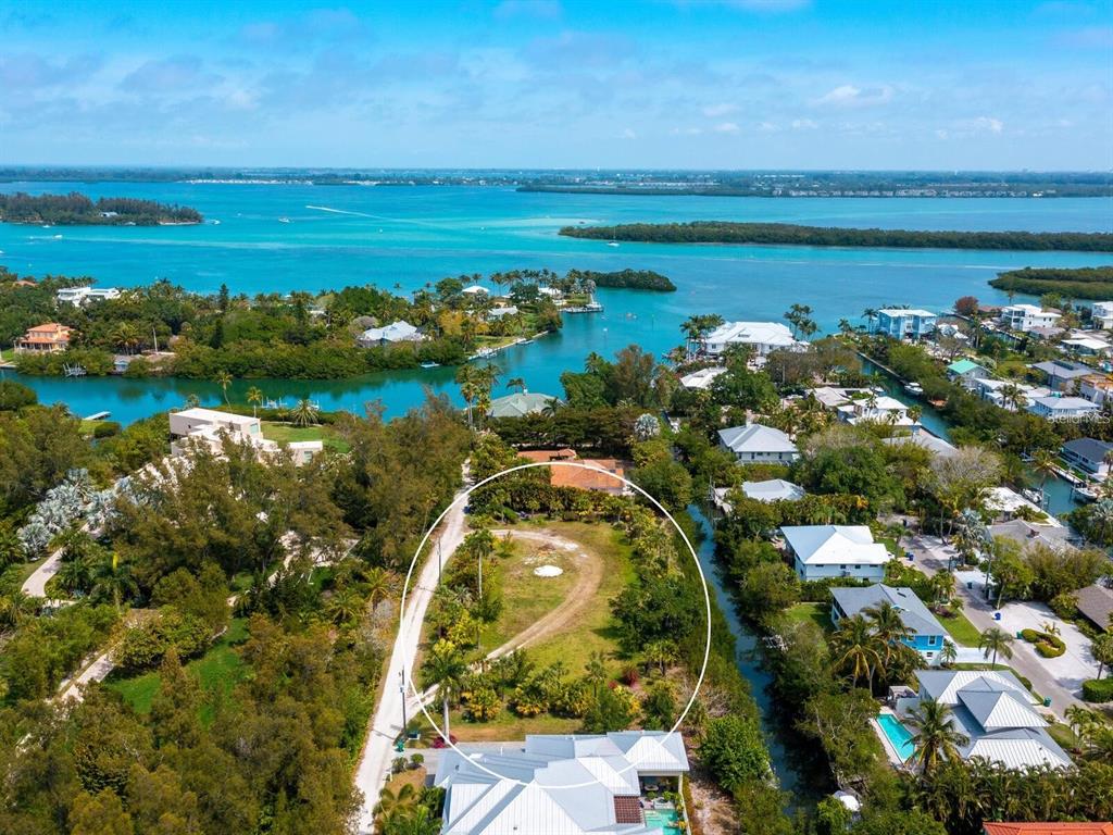 An aerial view shows a vacant, tree-lined lot circled in white near a coastal waterway — 6604-6608 GULF OF MEXICO DRIVE, LONGBOAT KEY, FL