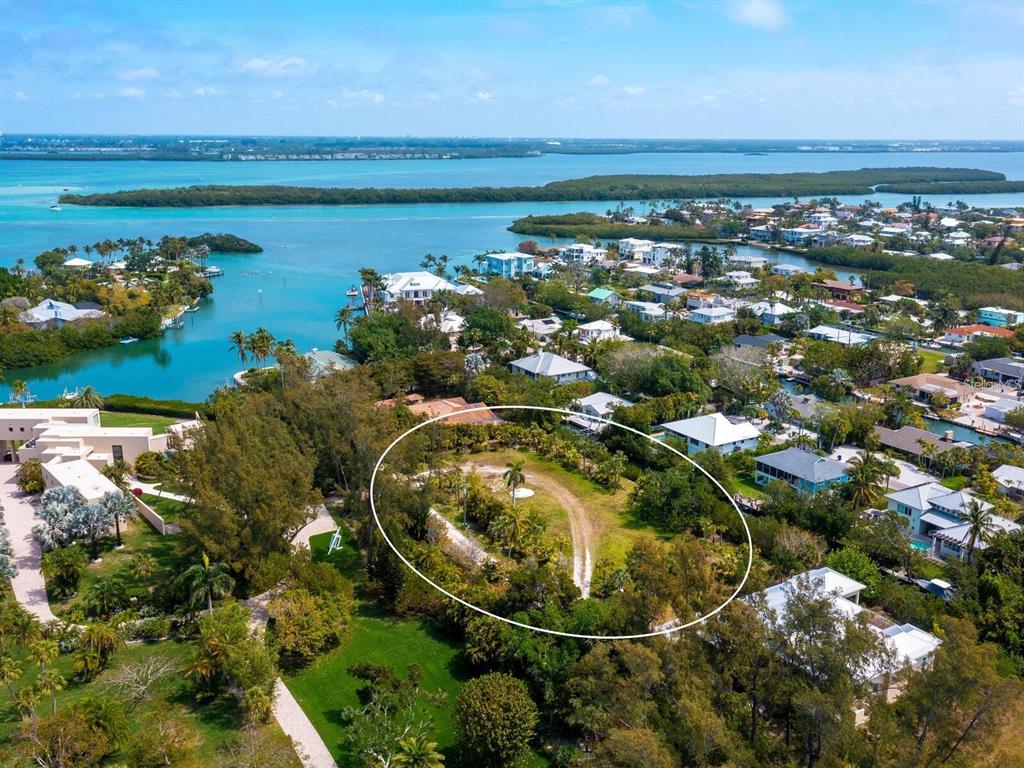 An aerial view shows a vacant, wooded lot circled in white near a coastal neighborhood — 6604-6608 GULF OF MEXICO DRIVE, LONGBOAT KEY, FL