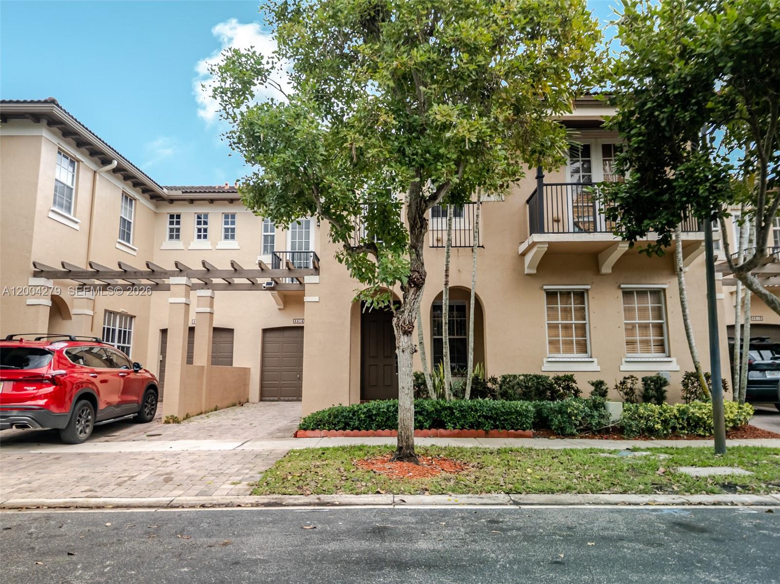 A two-story tan townhouse features a brown garage, a front door, and a balcony — 4414 Morgan Ln, Davie FL 33328, DAVIE, FL