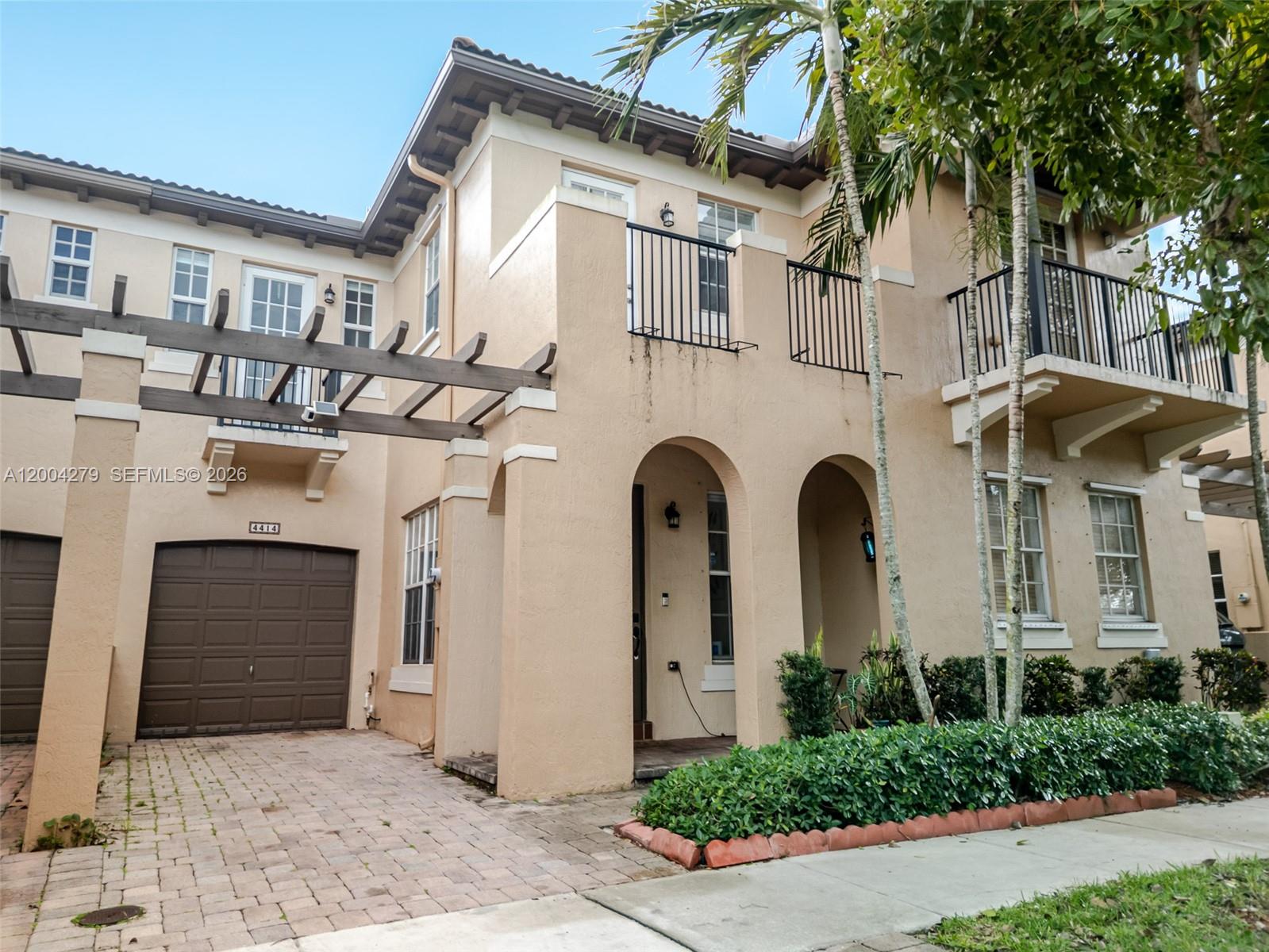 A two-story stucco townhouse features a brown garage, arched entryways, and upper-level balconies — 4414 Morgan Ln, Davie FL 33328, DAVIE, FL