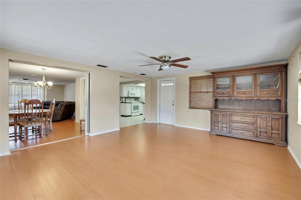 A spacious living area with light wood flooring, a ceiling fan, and a large wooden hutch — 3632 MORLEY DRIVE, NEW PORT RICHEY, FL