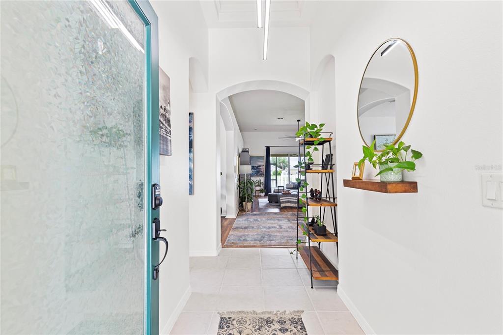 A bright entryway features a teal door, tiled floors, a wall shelf, and a metal shelving unit — 31415 BRIDGEGATE DRIVE, WESLEY CHAPEL, FL