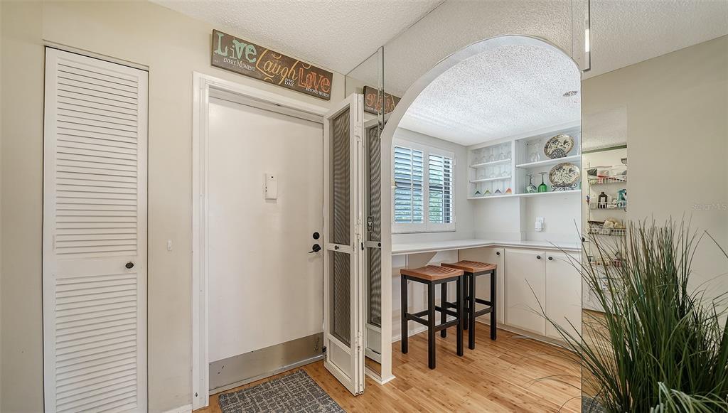 An entryway with a white door, louvered closet, and an arched opening to a breakfast nook — 8773 MIDNIGHT PASS ROAD UNIT 302G, SARASOTA, FL