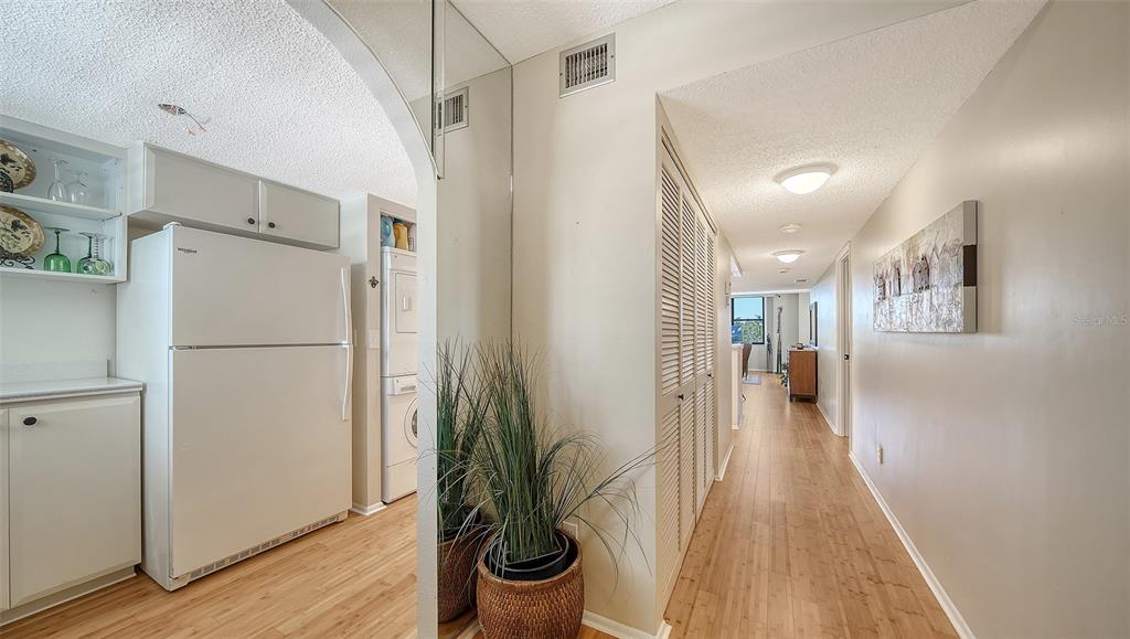 A hallway with wood-look flooring leads past a kitchen area with a white refrigerator — 8773 MIDNIGHT PASS ROAD UNIT 302G, SARASOTA, FL