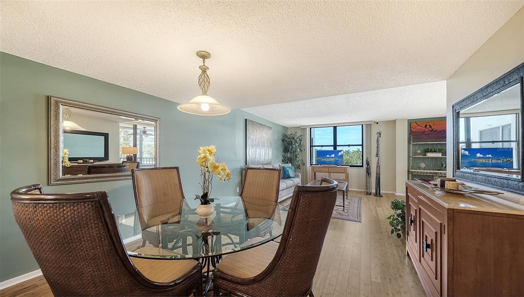 A dining area with a glass table and wicker chairs opens into a living room — 8773 MIDNIGHT PASS ROAD UNIT 302G, SARASOTA, FL
