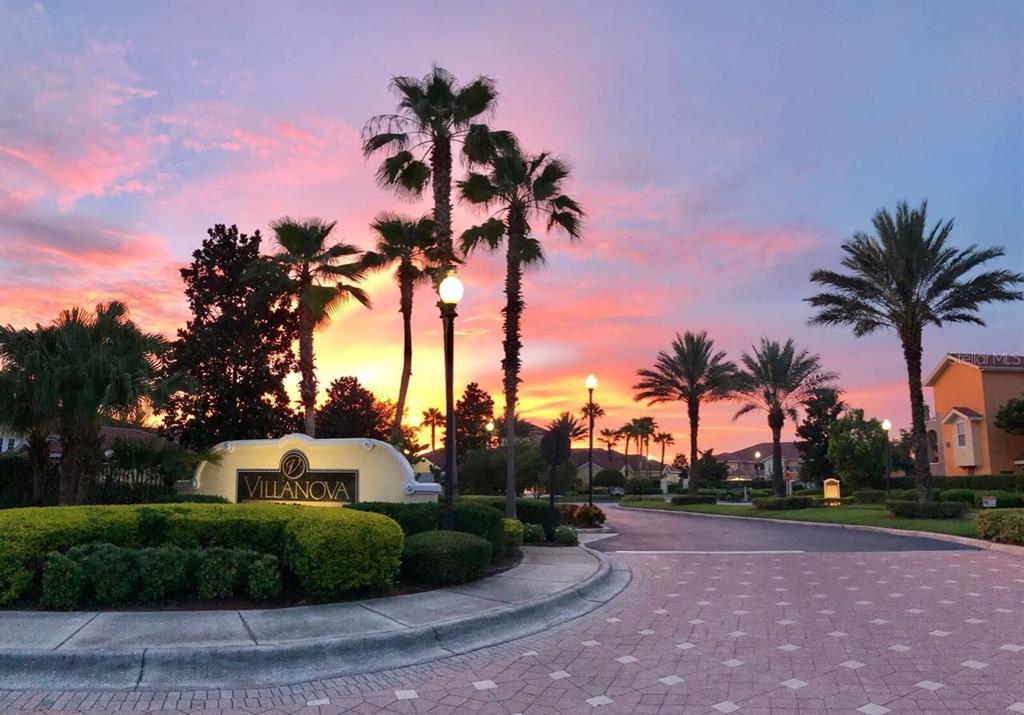 A sign for Villanova stands at the entrance of a community with palm trees at sunset — 12102 POPPY FIELD LANE UNIT 111, ORLANDO, FL