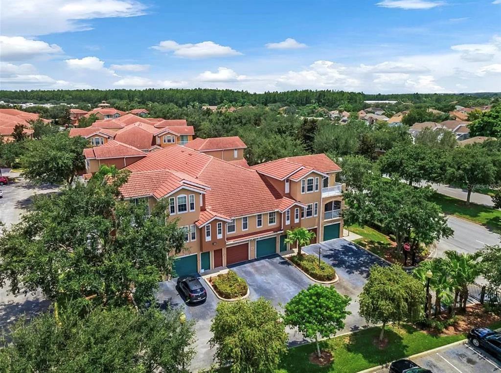 An aerial view of a multi-story residential building with a red tile roof and garages — 12102 POPPY FIELD LANE UNIT 111, ORLANDO, FL