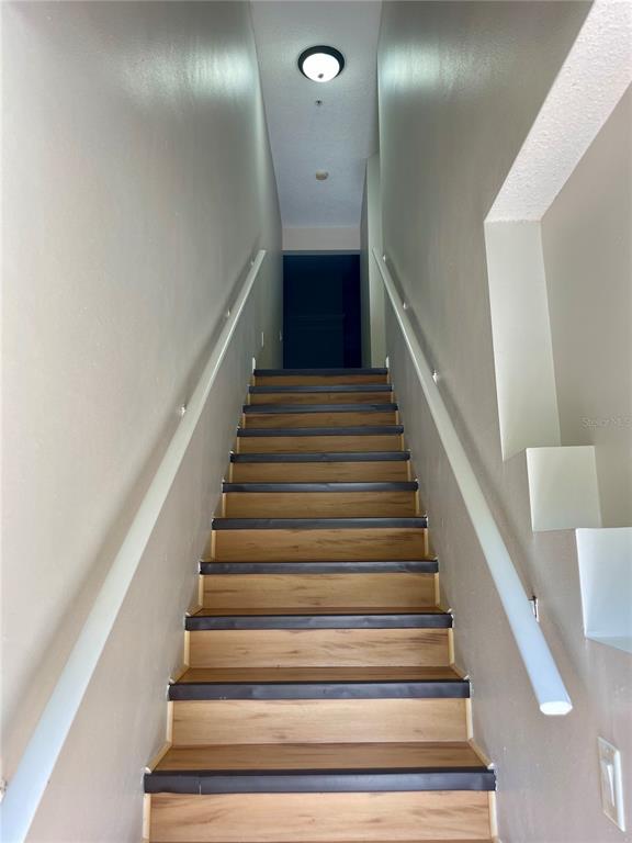 A straight staircase with wood-look treads and white handrails leads to an upper landing — 12102 POPPY FIELD LANE UNIT 111, ORLANDO, FL