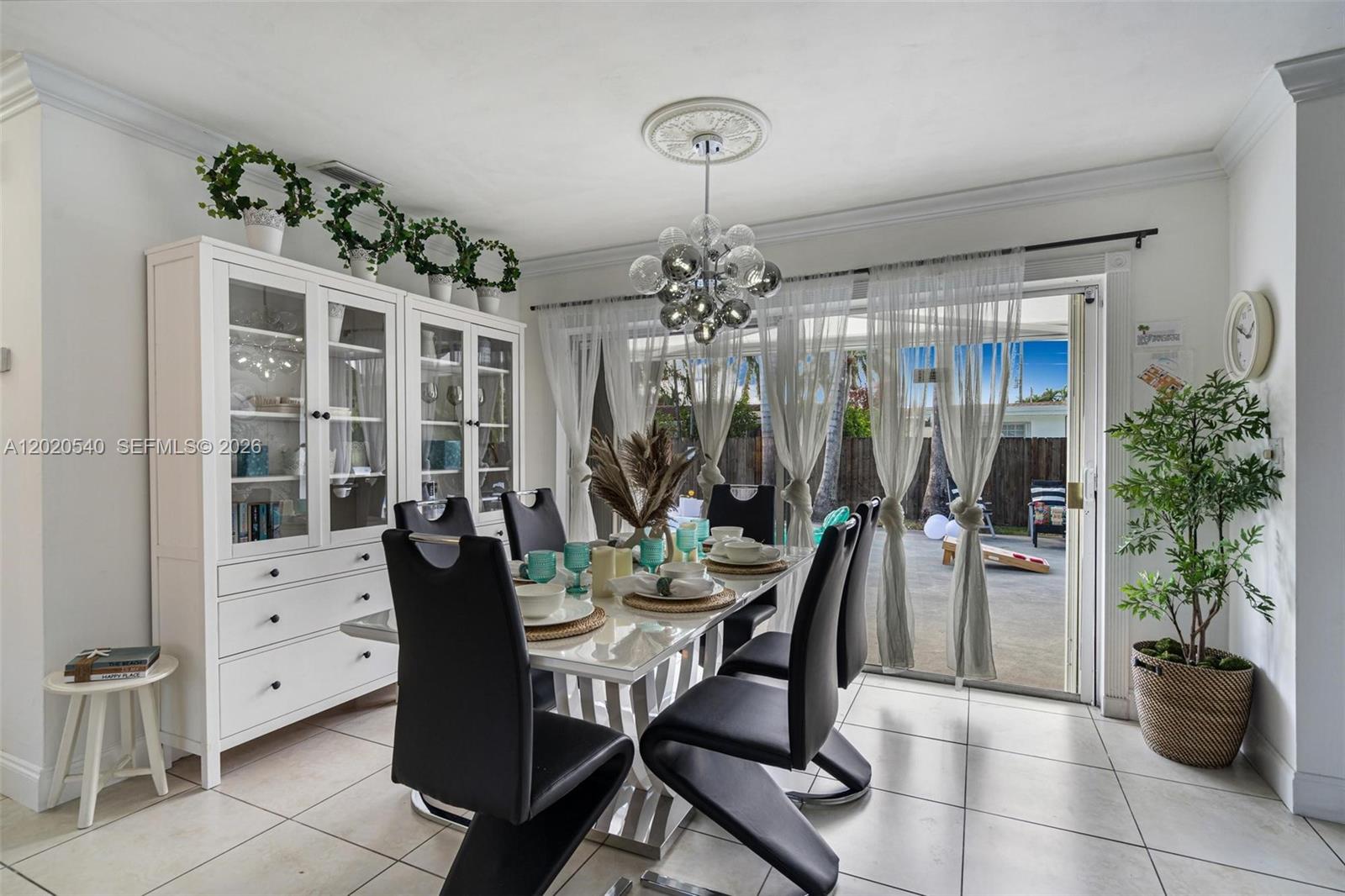 A dining room features a white hutch, black chairs, a glass table, and sliding glass doors — 1012 N 13th Ter, Hollywood FL 33019, HOLLYWOOD, FL