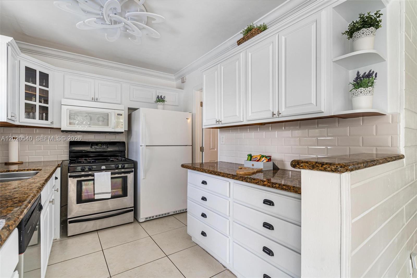 A kitchen features white cabinets, granite countertops, stainless steel appliances, and light-colored tile flooring — 1012 N 13th Ter, Hollywood FL 33019, HOLLYWOOD, FL
