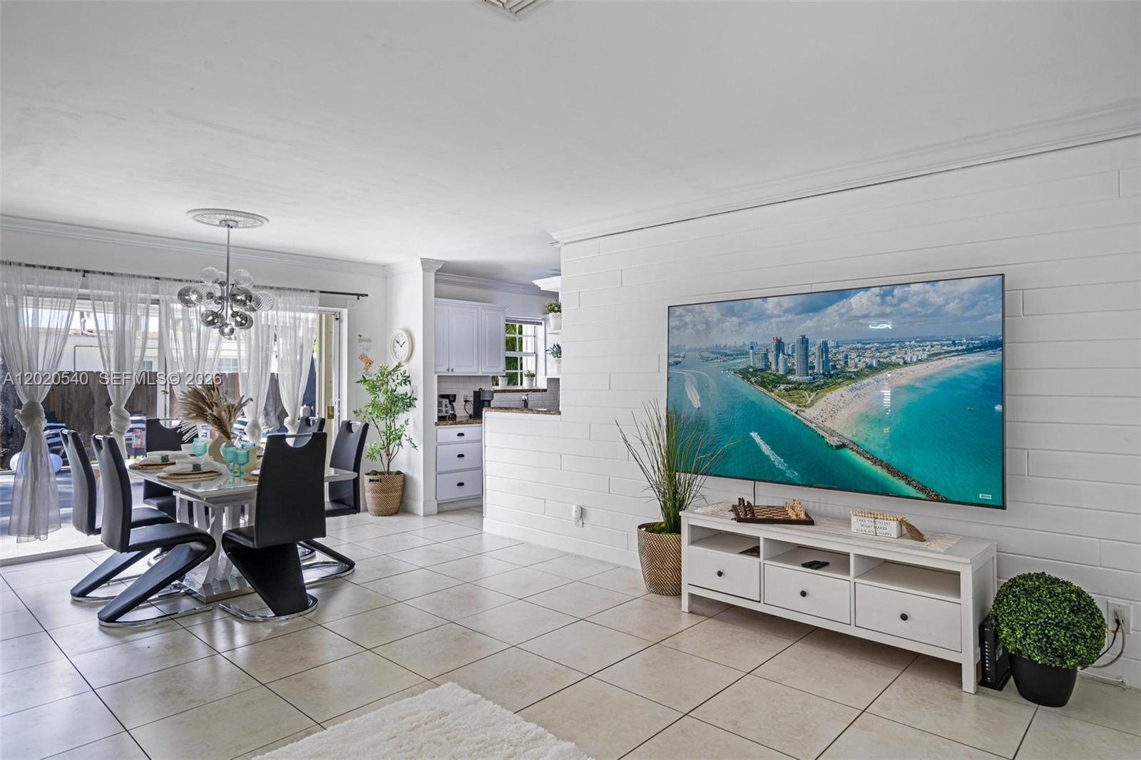 A dining area and living room feature white shiplap walls, tile flooring, and a large television — 1012 N 13th Ter, Hollywood FL 33019, HOLLYWOOD, FL