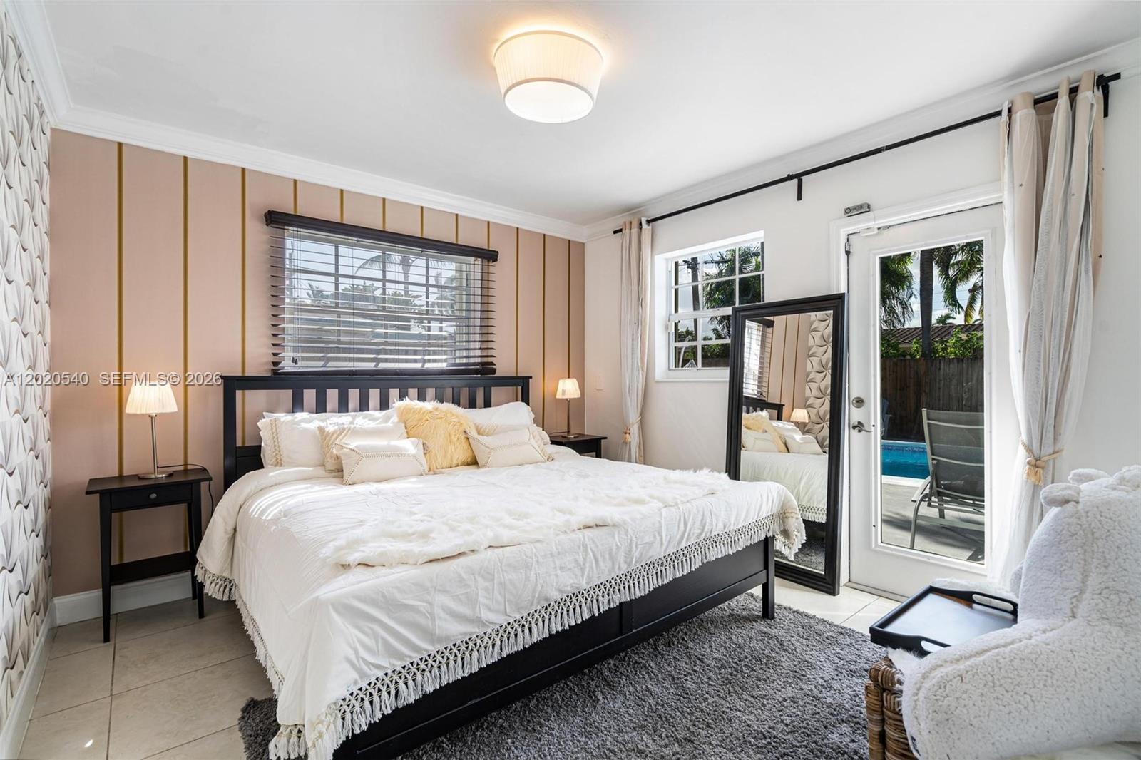 A bedroom features a bed with white bedding, a pink accent wall, and a pool view — 1012 N 13th Ter, Hollywood FL 33019, HOLLYWOOD, FL