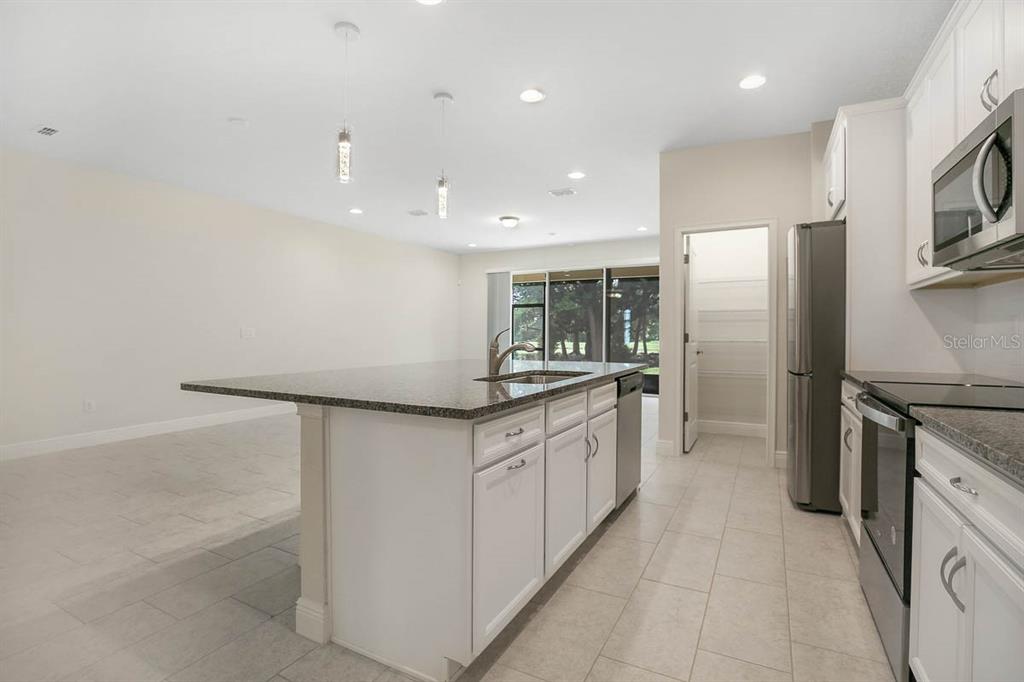 A kitchen with white cabinets, granite countertops, a center island, and stainless steel appliances — 10232 NEWEL VALLEY LOOP, RIVERVIEW, FL