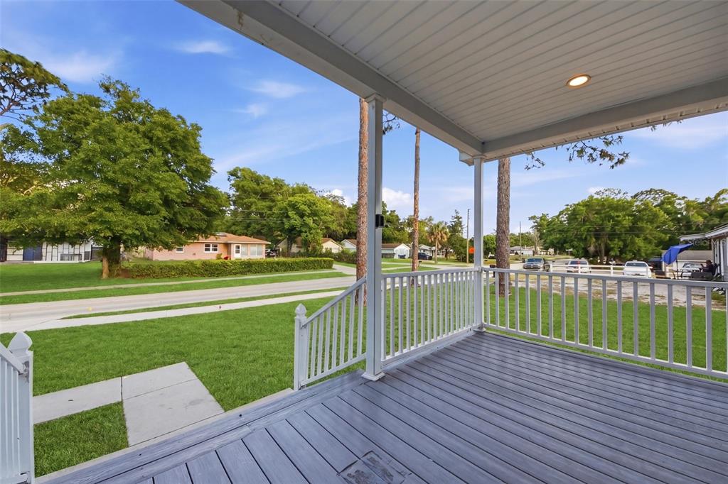 A covered wooden porch overlooks a grassy front yard and a residential street — 5430 ROSE AVENUE, ORLANDO, FL