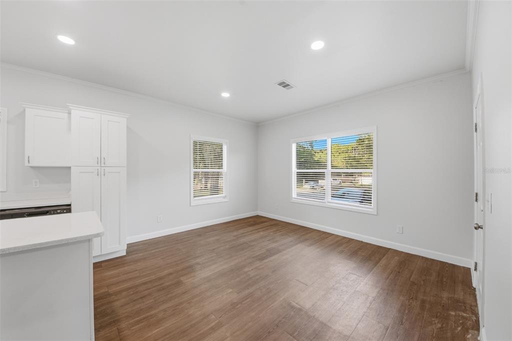 A bright kitchen and dining area features white cabinets, light walls, and wood-look flooring — 5430 ROSE AVENUE, ORLANDO, FL