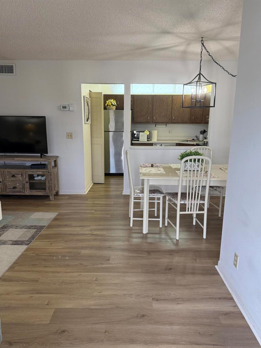 A dining area with a white table and chairs sits adjacent to a galley kitchen — 133 Lake Pine Circle # 2, FL 33463, FL