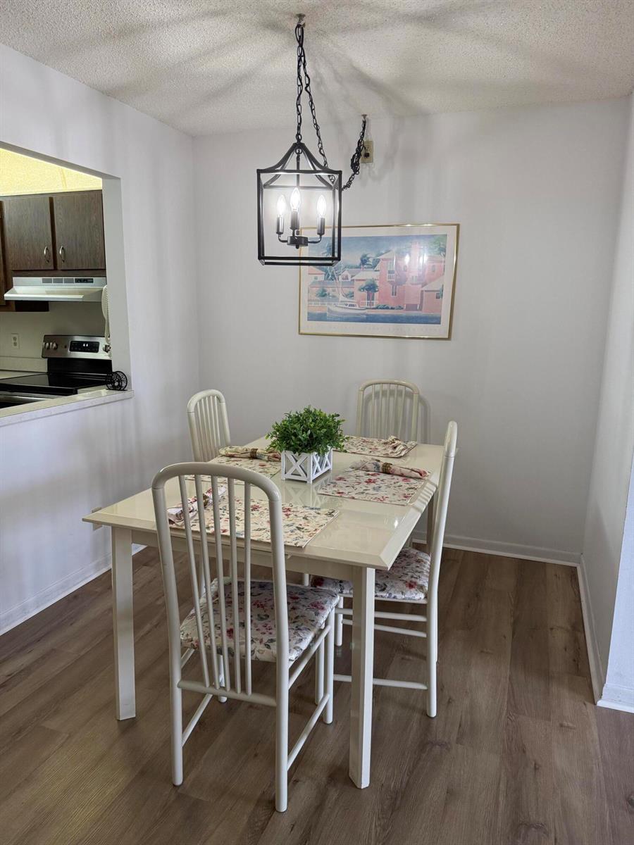 A dining area features a white table with four chairs, a pendant light, and artwork — 133 Lake Pine Circle # 2, FL 33463, FL