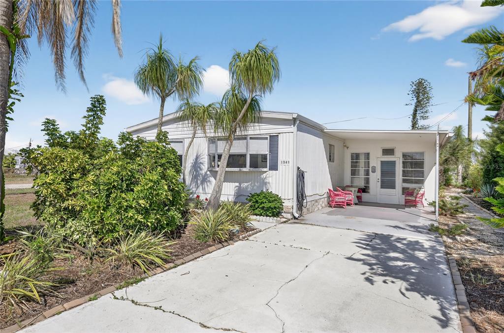 A single-story mobile home with a concrete driveway, carport, and palm trees in the front yard — 1349 SEAGULL DRIVE, ENGLEWOOD, FL