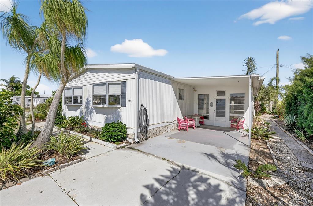 A single-story mobile home with white siding, a concrete driveway, and a covered front patio — 1349 SEAGULL DRIVE, ENGLEWOOD, FL
