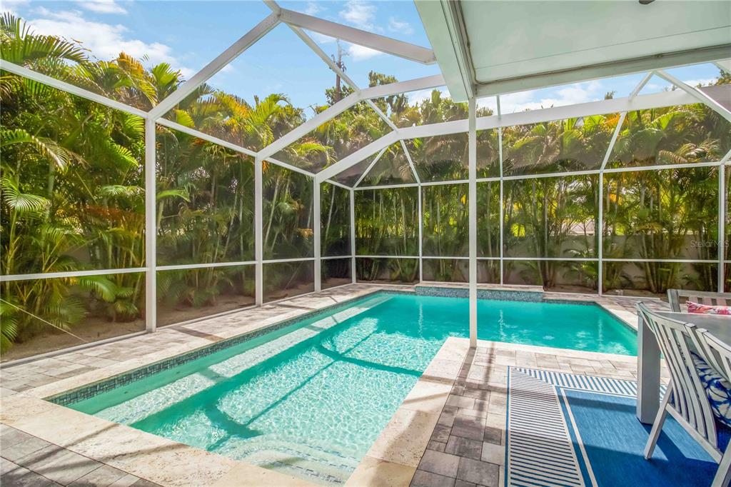A rectangular swimming pool with a tiled deck is enclosed by a white screen cage — 2373 PROSPECT STREET, SARASOTA, FL
