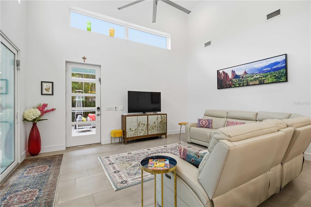 A modern living room features high ceilings, a white door, and a light-colored sectional sofa — 2373 PROSPECT STREET, SARASOTA, FL