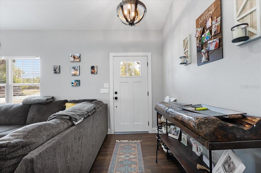 A living room entryway features a white front door, dark wood flooring, and a console table — 5231 NW 73RD STREET, CHIEFLAND, FL